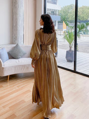 Woman in a long, gold dress standing in a modern living room.