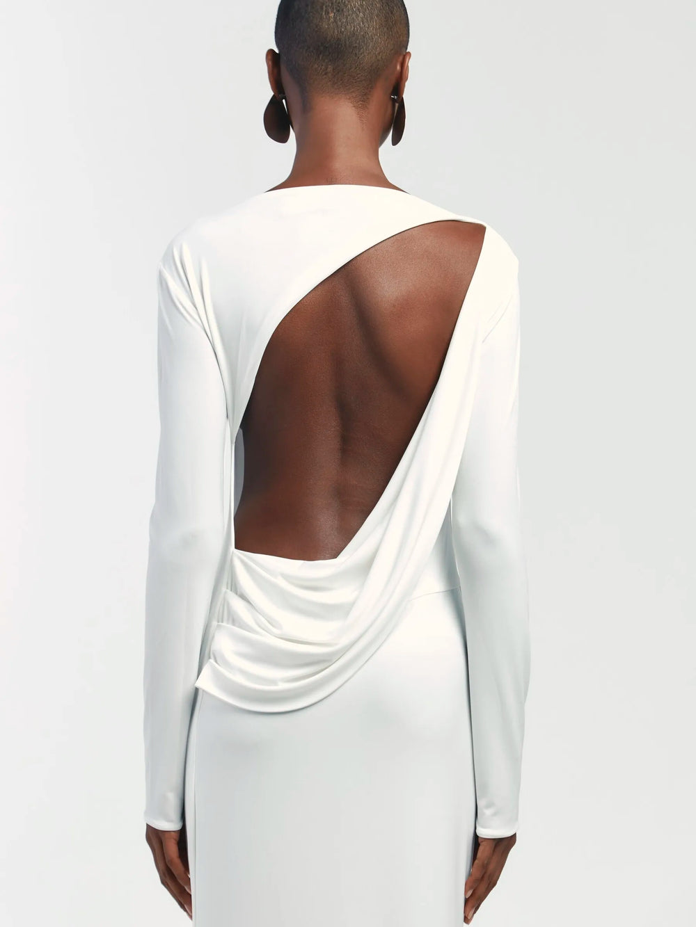 White long-sleeve top with open back on a plain background