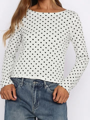 White long-sleeve top with black polka dots worn by a person, against a plain background