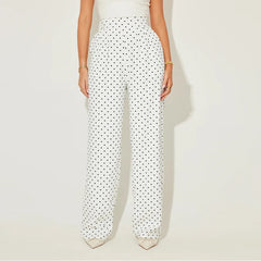 White pants with black polka dots worn by a person on a light beige background