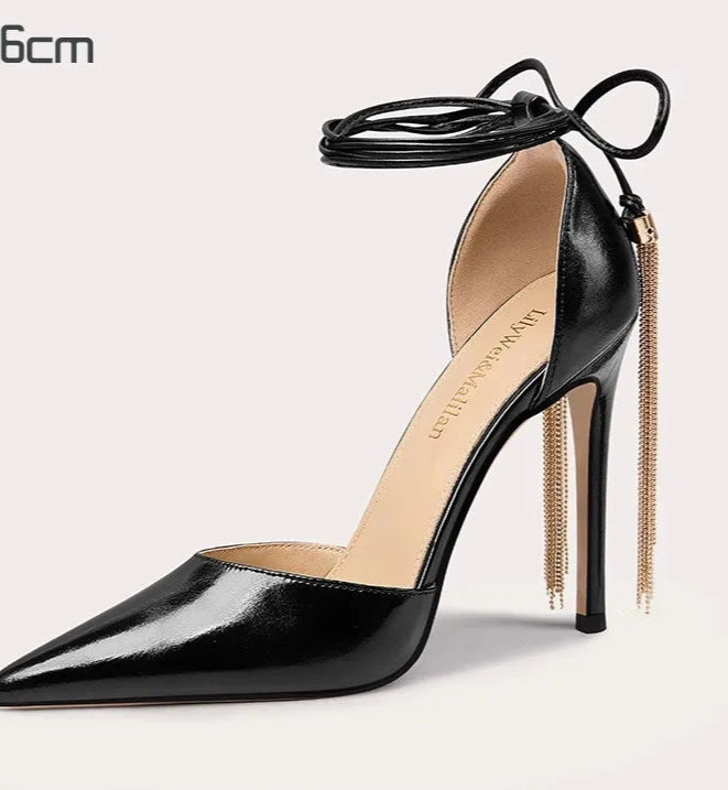 Black high-heeled shoe with a gold chain on a light gray background