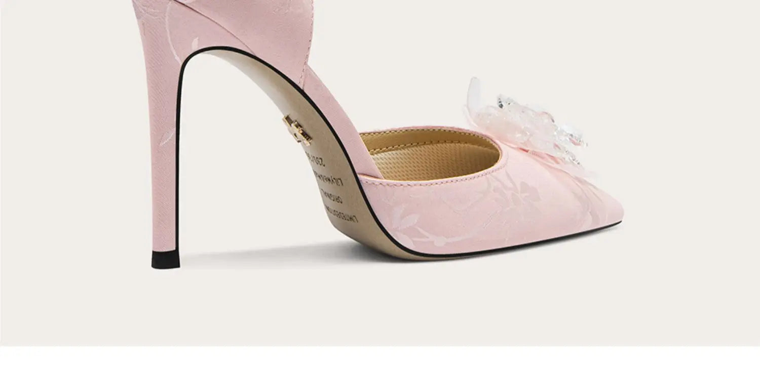 Pink high-heeled shoe with a decorative bow on a light pink background