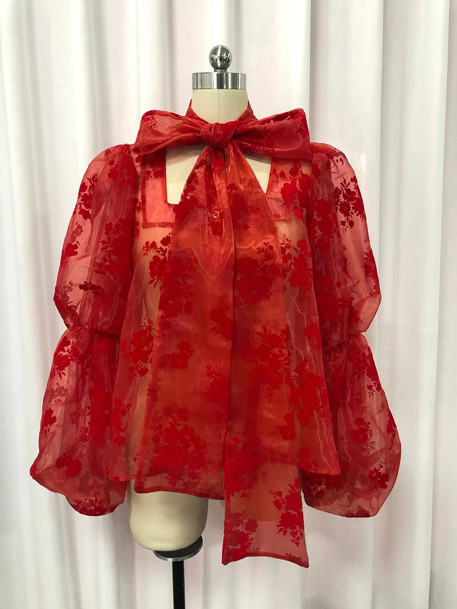 Red floral blouse on a mannequin against a white curtain background