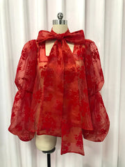 Red floral blouse on a mannequin against a white curtain background