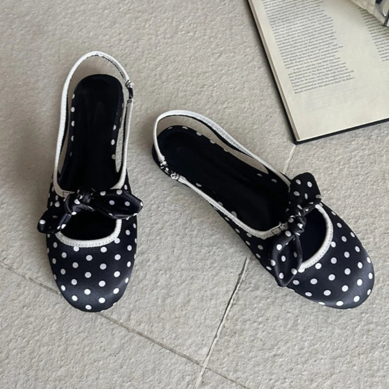Black polka dot slingback pumps with a bow accent.