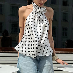 Woman wearing a polka dot halter top and jeans outdoors.