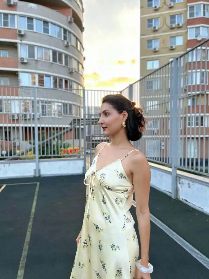 Woman in a floral dress standing on a rooftop with apartment buildings in the background