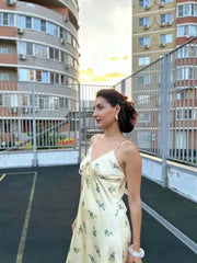 Woman in a floral dress standing on a rooftop with apartment buildings in the background
