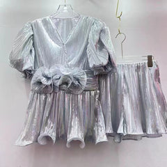 Silver metallic dress with puff sleeves and a matching skirt on hangers against a white background
