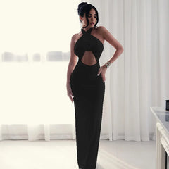 Woman in a black evening gown standing in a room with white curtains.