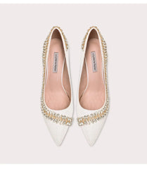 White pointed-toe shoes with embellishments on a light gray background