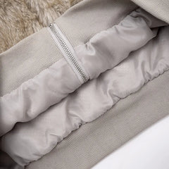 Close-up of a light gray puffer jacket with a fur-lined hood on a neutral background