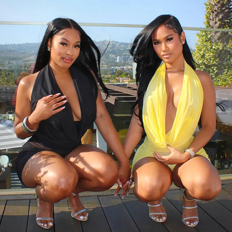 Two women posing outdoors on a wooden deck with a scenic background.