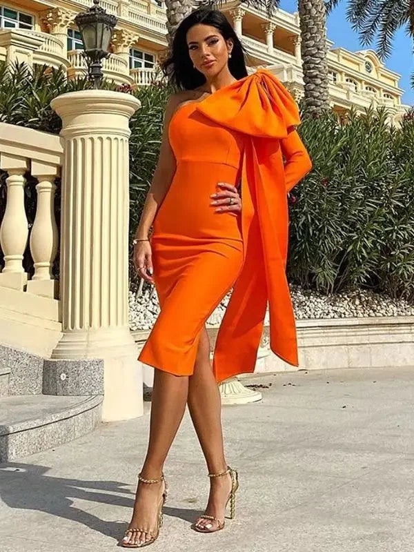 Woman in an orange dress standing outdoors with classical architecture in the background