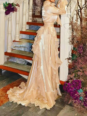 Woman in a beige evening gown standing on a staircase with flowers around