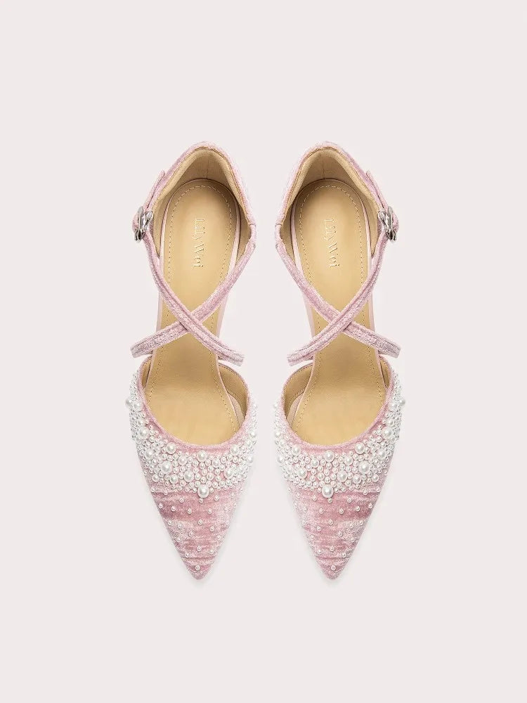 Pair of pink high-heeled shoes with beaded details on a light gray background