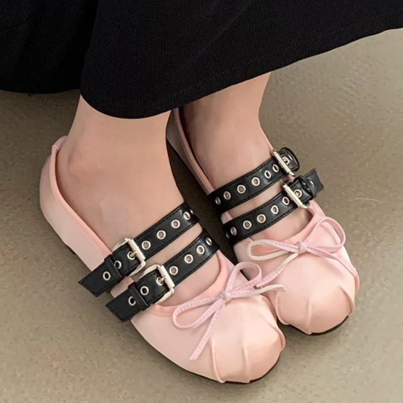 Pink silk ballet flats with double buckle straps and butterfly knot on a foot