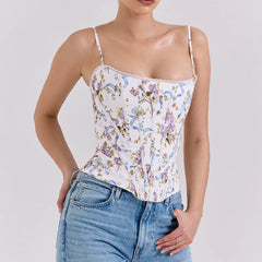 Woman wearing a floral camisole top and jeans on a plain background