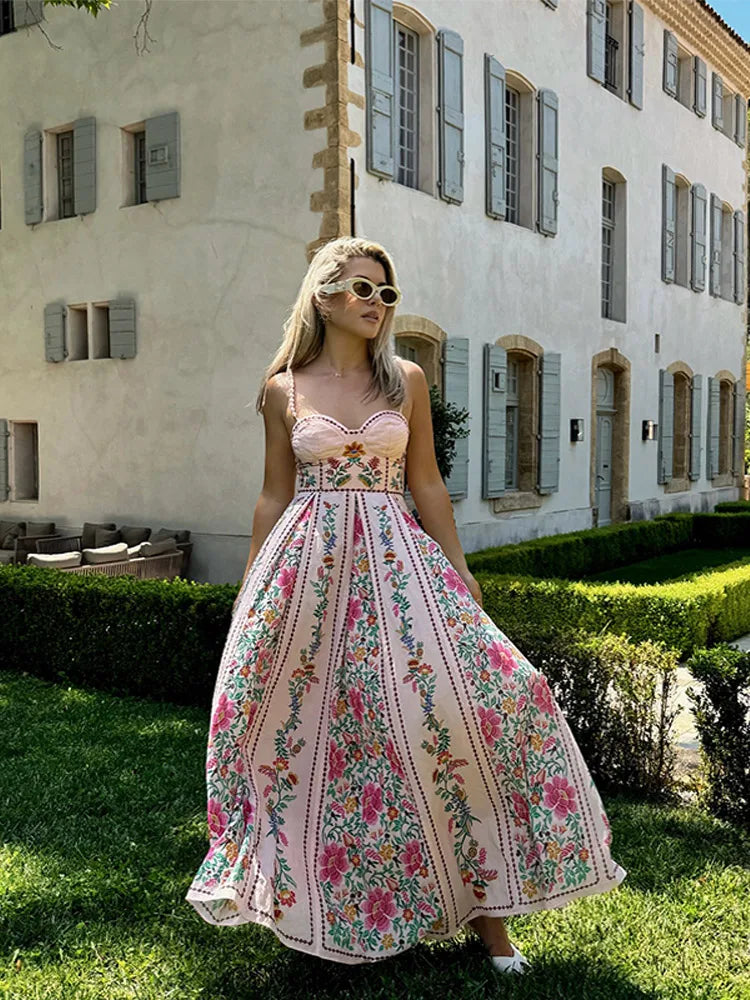 Woman in a floral dress standing in front of a building with greenery