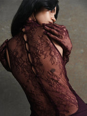 Person wearing a dark lace garment against a neutral background