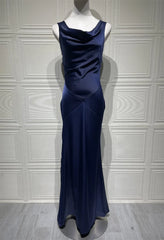 Navy blue evening gown on a mannequin against a white paneled wall.