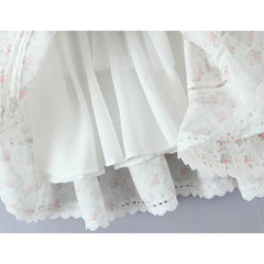 Close-up of a white lace skirt with floral patterns on a light gray background