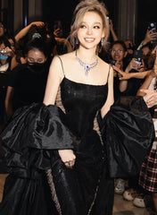 Woman in a black evening gown with puffed sleeves at an event.
