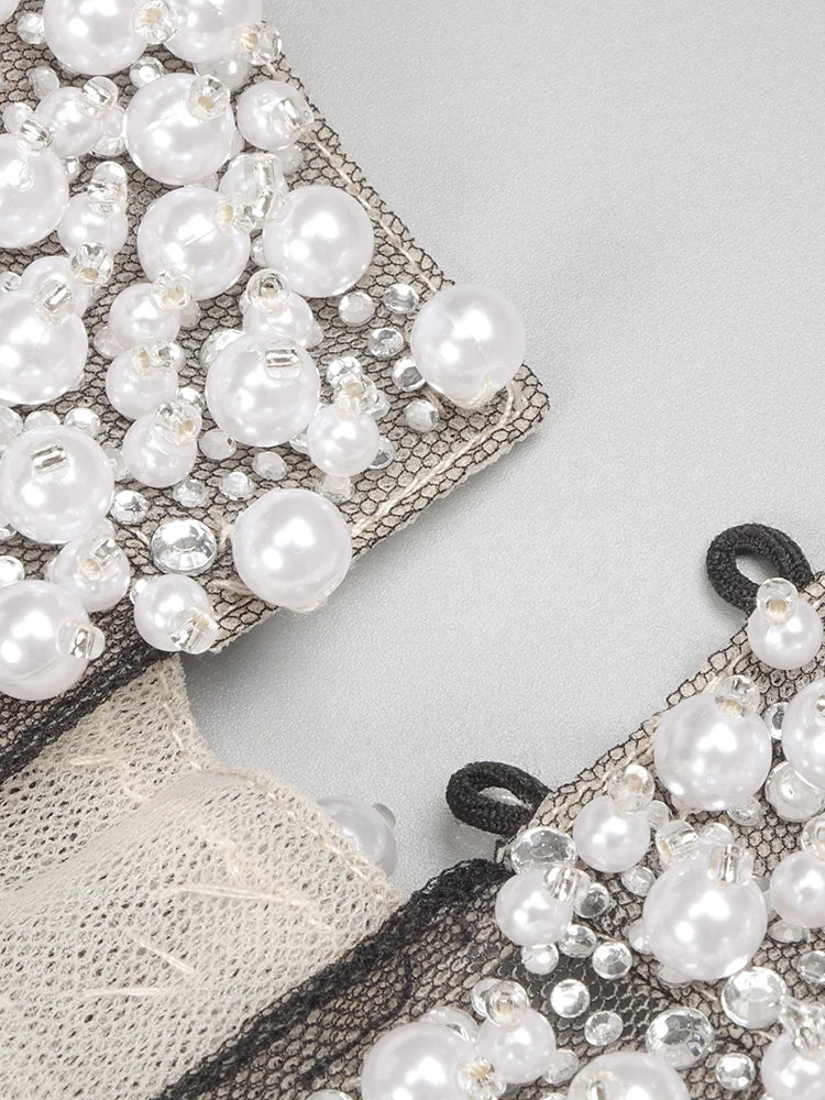 Close-up of a decorative fabric with pearls and lace on a light gray background