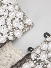 Close-up of a decorative fabric with pearls and lace on a light gray background