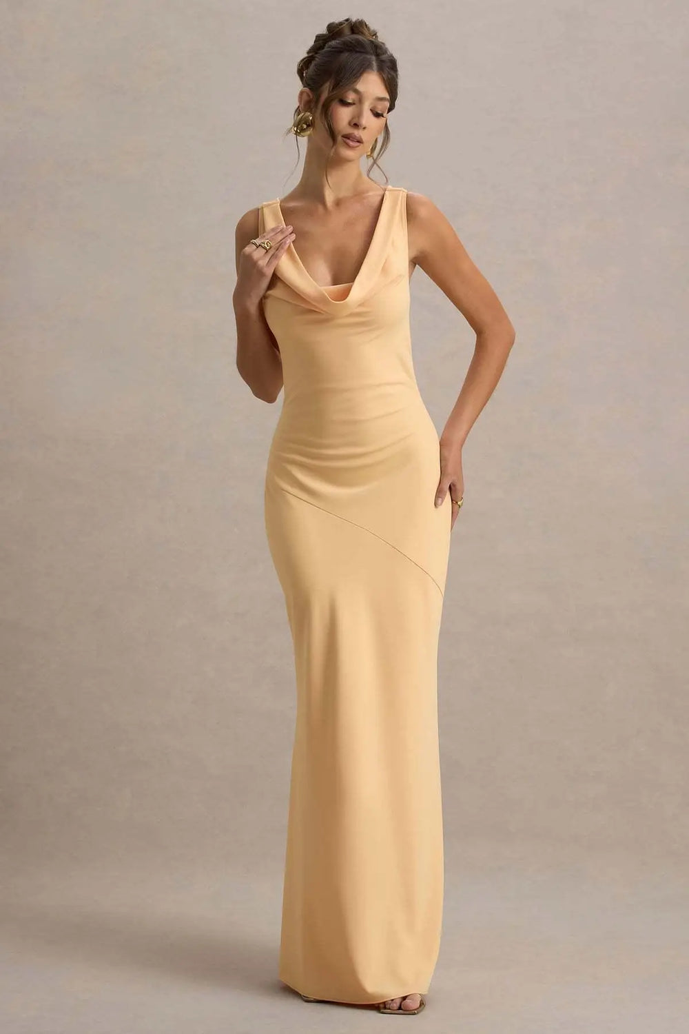 Woman wearing a long yellow dress against a neutral background