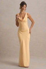 Woman wearing a long yellow dress against a neutral background
