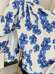 White fabric with blue floral pattern draped over a chair.