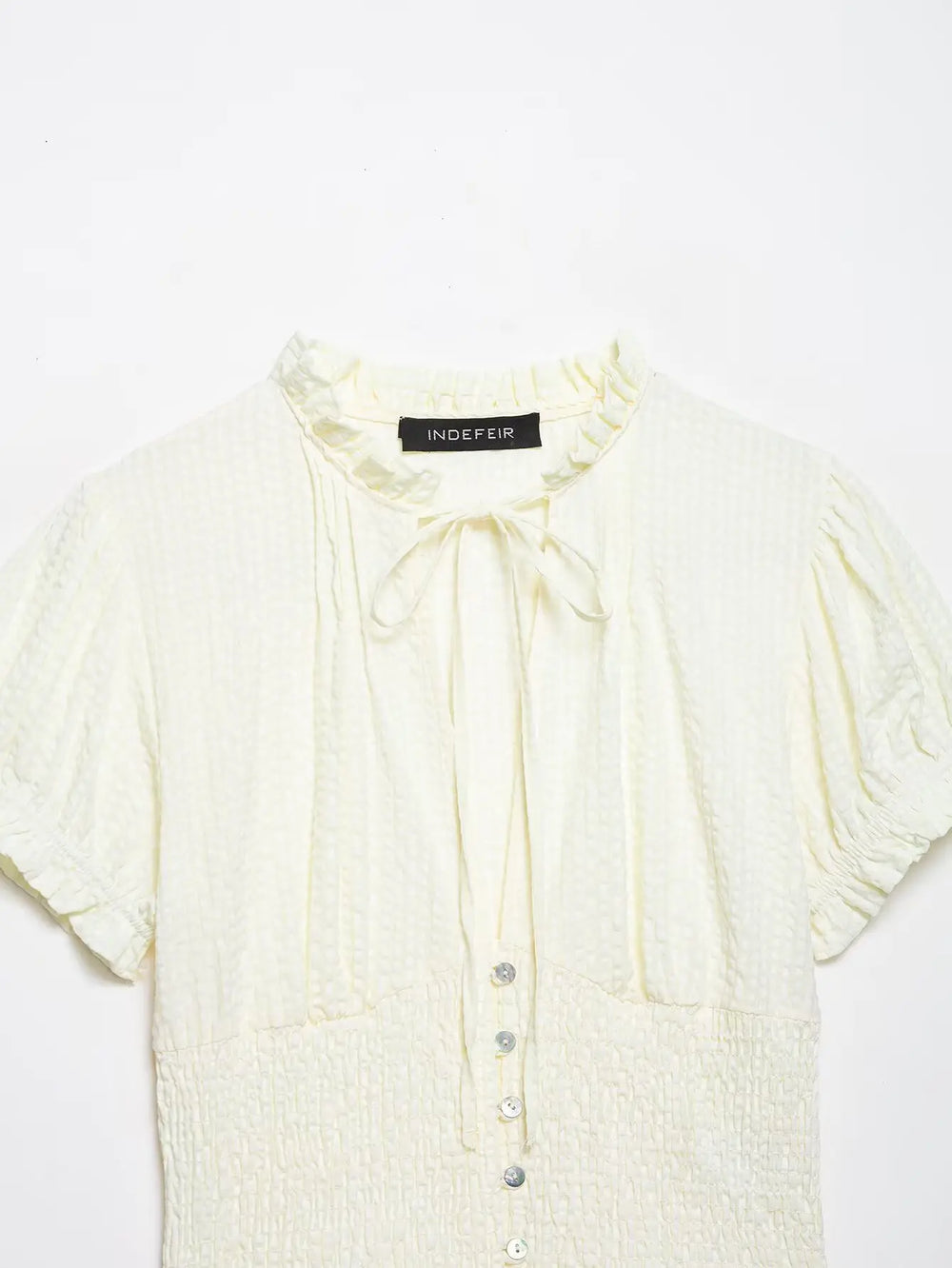 Light yellow blouse with buttons on a white background