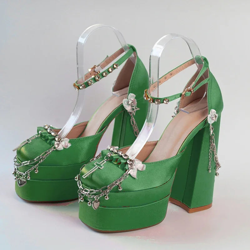 Green high-heeled shoes with clear straps and decorative elements on a light gray background