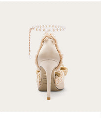 Beige high-heeled shoe with decorative elements on a white background