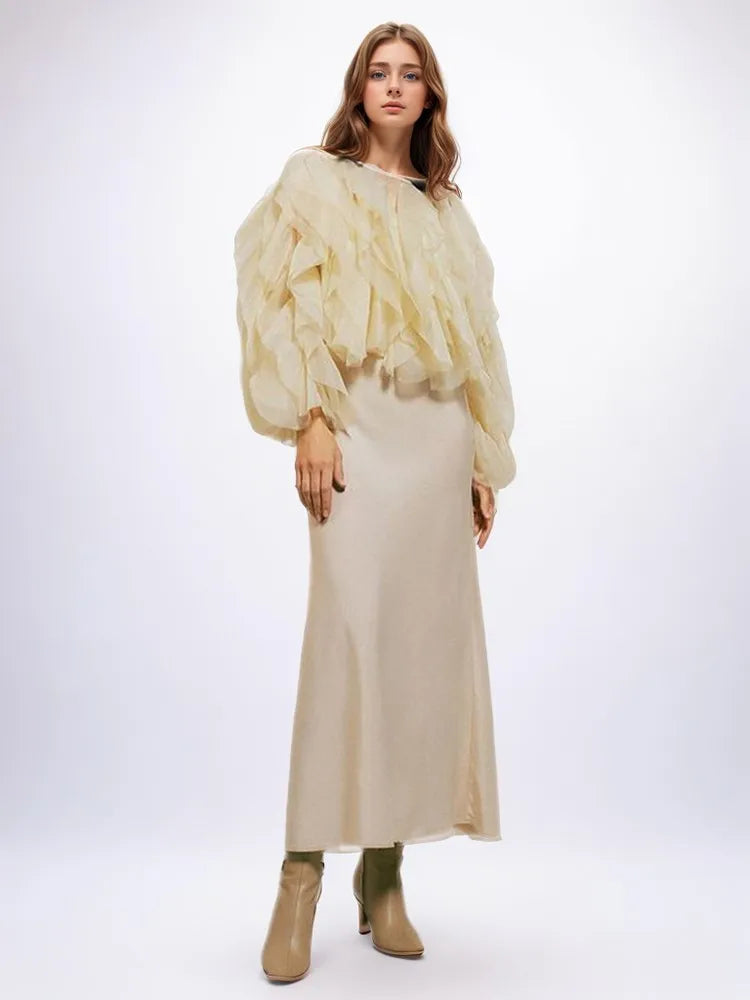 Woman wearing a beige outfit with a ruffled top on a white background