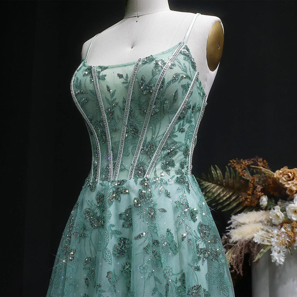 Teal evening gown with floral and bead details on a mannequin against a dark background.