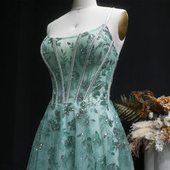 Teal evening gown with floral and bead details on a mannequin against a dark background.