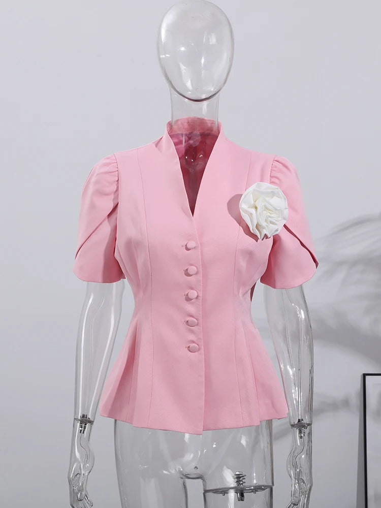 Pink blazer with white flower accessory on a mannequin against a plain background