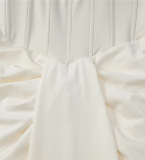 Close-up of a white dress with a bow detail on a light gray background