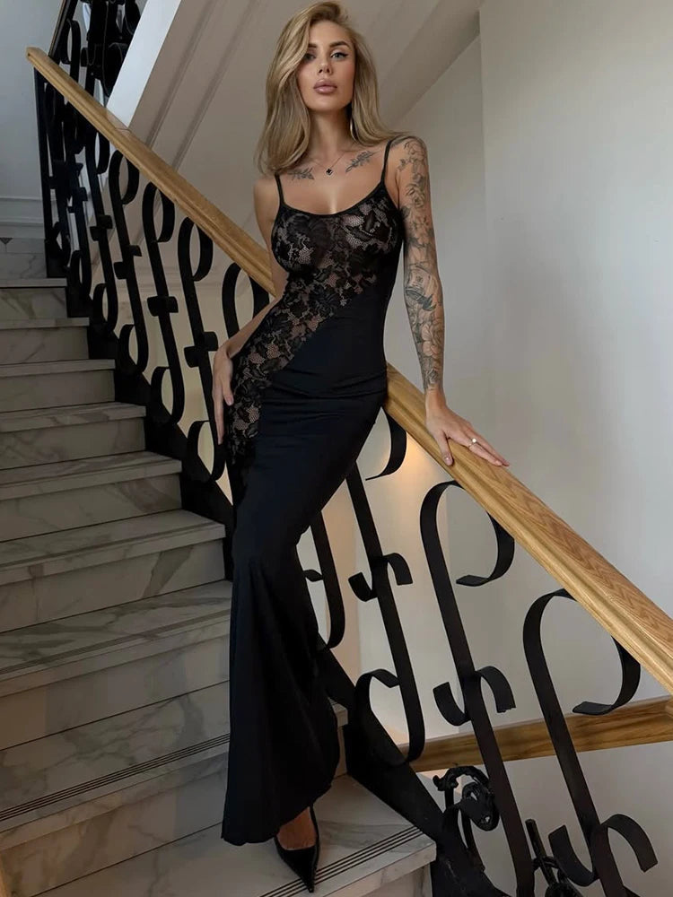 Woman in a black and floral dress standing on a staircase with decorative railings.