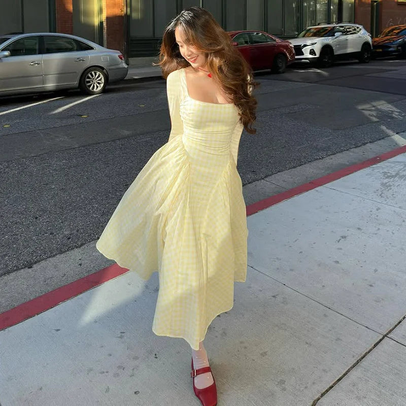 Woman in a light yellow dress standing on a city street.