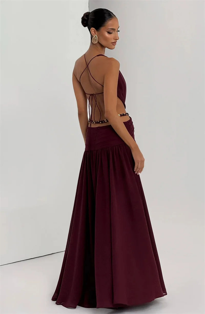 Woman wearing a burgundy evening gown with intricate back design on a white background