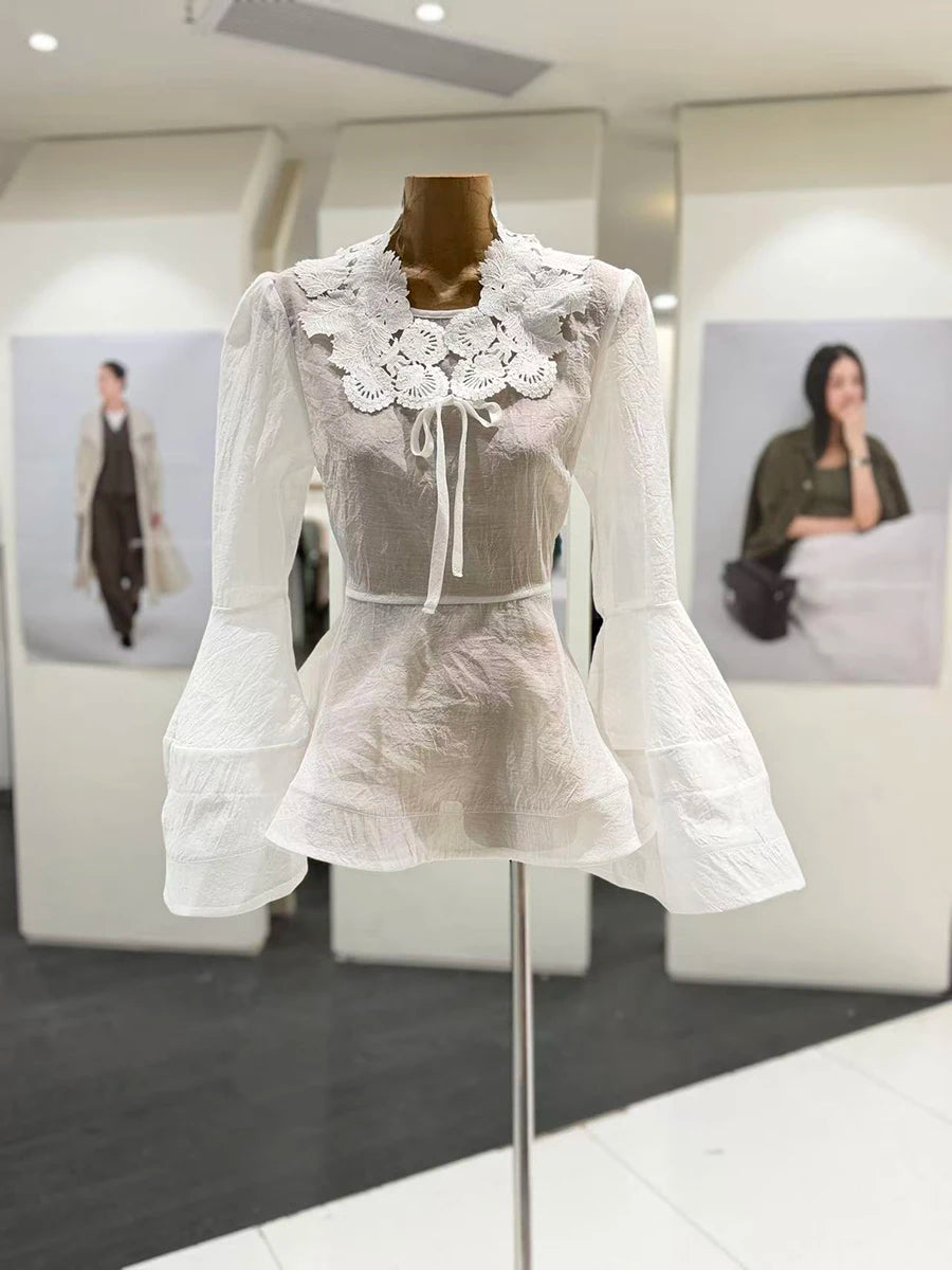 White lace dress on a mannequin in an indoor setting with blurred background