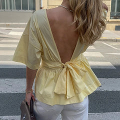 Woman wearing a yellow open-back top on a street.