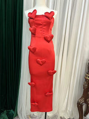 Red dress with heart designs on a mannequin against a white curtain background