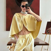 Woman in a yellow outfit taking a mirror selfie in a modern interior setting.