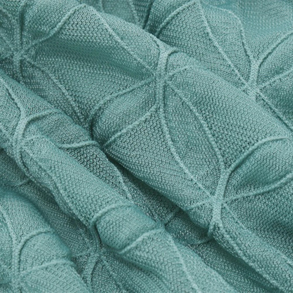 Close-up of a textured teal fabric with leaf patterns