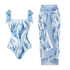 One-piece swimsuit with blue scale print and tie straps, paired with a wrap-style skirt with matching print.