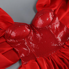 Close-up of a red dress with sequin details on a gray background